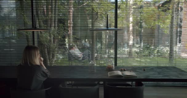 Вид Сзади Женщину Сидящую Кресле Столом Смотрящую Панорамное Окно Дом — стоковое видео