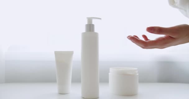 用干净的手在白色房间的背景上按奶瓶上的手指按钮 靠近点女用手推送泵塑料乳液瓶 在手上涂保湿霜 — 图库视频影像