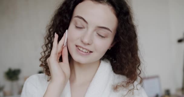 漂亮的女人拿着棉垫 去除杂质 清洁她完美的皮肤 在家进行护理和清洁 用乳液给皮肤润肤 护肤身体护理 皮肤科 — 图库视频影像