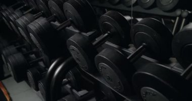 Modern spor salonunda ağırlık çalışması için askıda duran demir dambıllar. Spor malzemeleriyle spor salonunda ağırlık antrenmanı yapın..