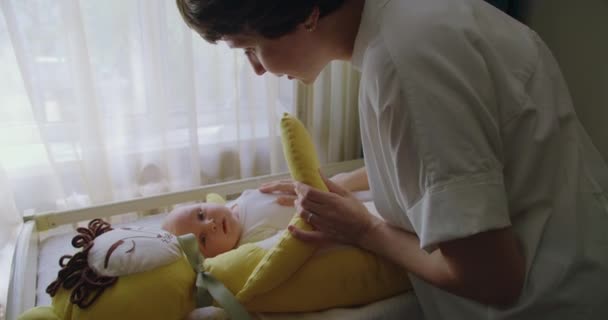 幼い赤ん坊は目を覚まし 柔らかいおもちゃと母親の近くのベビーベッドで泣き 素敵な新生児を癒し 胃をストロッキングし 柔らかく話します 母性コンセプト — ストック動画