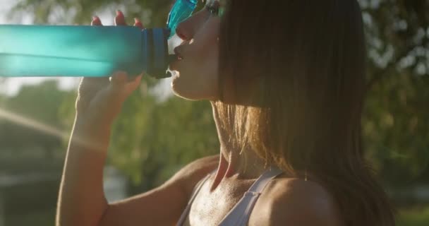 운동에 휴식을 취하고 화창한 공원에서 마시는 여자의 상쾌한 — 비디오