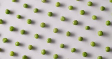 Fresh green peas placed side by side rotate on a white platform. Raw green peas in motion on isolated white background rotating with same motion.