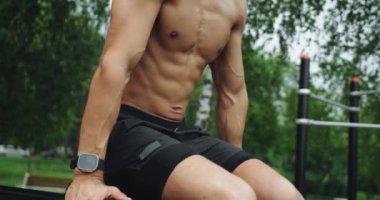 Paralel barda atletizm eğitimi ve spor sahasında karın kasları egzersizi. Vücut çalışmasında erkek, üstsüz ve karın kasları mükemmel..