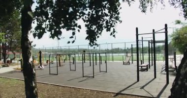 Açık hava spor salonu. Güneşli yaz gününde şehir parkındaki spor sahasında spor yapmak için yatay barlara ve modern egzersiz ekipmanlarına bakın.