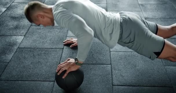 Junger Mann Sportbekleidung Trainiert Körpermuskeln Fitnessstudio Und Liegestütze Mit Medizinball — Stockvideo