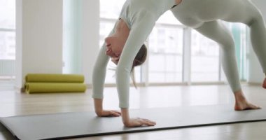 Paspasın üzerinde uzanan genç bir kadın. Aktif giyimli, çıplak ayaklı genç bir kadının sabah yoga seansı sırasında mindere poz verirken ve esneme hareketleri yaparken elde çekilmiş bir fotoğrafı..