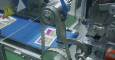 Tıp fabrikasında üretim hattı. Robot kol, ilaç paketini taşıma bandına koydu. Otomatik üretim hattında paketlenmiş mallar. İlaç imalatının üretim hattı.