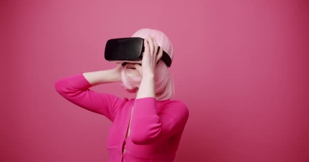 女人使用虚拟的现实眼镜 在孤立的粉色背景下寻找和触摸虚拟的生活 未来的概念 生活方式 粉色的颜色 现代女性 — 图库视频影像