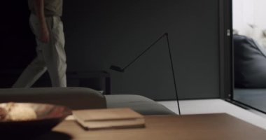 Manzaralı adam açık kapılı odayı terk ediyor. Modern dairede yürüyen kişi, bacaklara odaklanır..