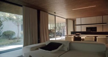 Kır evi, konforlu kanepe ve yastıklı oda, sandalyeli yemek masası, ev aletli mutfak alanı, panoramik pencere veya cam duvar ve dışarıda park edilmiş araba.