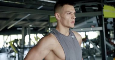 Genç vücut geliştirici modern spor salonunda egzersiz, ayakta durmak ve nefes almak için ara veriyor. Motive olmuş atletik erkek antrenmanda yorgun, dinleniyor ve fitness kulübündeki bir sonraki egzersize hazırlanıyor..