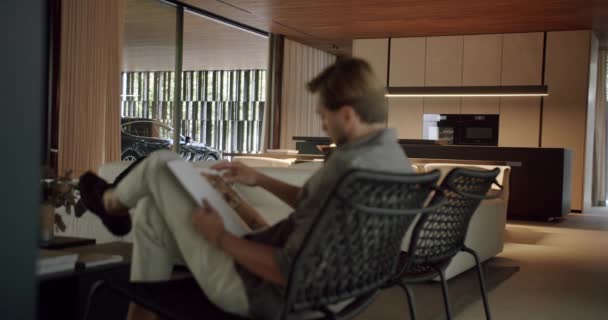 Homem Desfocado Sentado Cadeira Ler Revista Foco Fundo Apartamento Com — Vídeo de Stock
