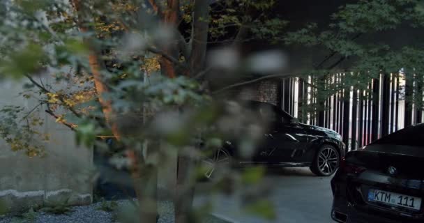 近代的な住宅の近くのガレージに駐車された高級黒い車 自動車のための家の駐車アイデア — ストック動画