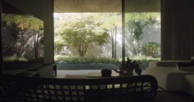 Bahçe bahçesi manzaralı, cam duvarlı lüks bir daire. Günümüz tatil evinde televizyon ekranı, kahve masası, rahat kanepe ve sandalye olan bir salon..