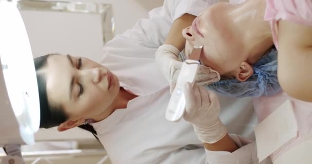 Profesjonalny Kosmetolog Robiący Usg Peeling Twarzy Dla Klientki Klinice Kosmetycznej — Wideo stockowe