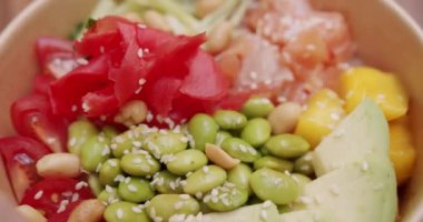 Somon, pirinç, avokado, edamame fasulyesi, ahşap zemin üzerinde salatalık. Sağlıklı yemek, keto diyeti konsepti. Asya çiğ yemeği. Poke kasesi, geleneksel Hawaii çiğ balık salatası. Japon yemeği..