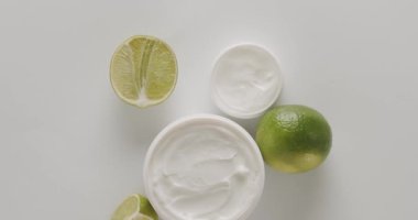Kavanozun üstünde beyaz arka planda taze limonun yanında hidrasyon kremi var. Yüz bakımı için doğal malzemelerle cilt bakımı. Reklam kavramı