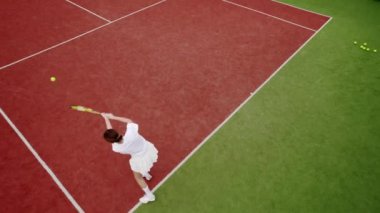 Havadan, yukarıdan aşağıya, İHA atışı. Bir kadın profesyonel ve dinamik olarak yavaş çekimde tenis oynar. Hafta sonları ve pazar günleri dinlenmek için. Arkadaşlarla aktif spor oyunu. Tenis oyuncusu iş başında.