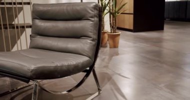 Oturma odasında modern gri deri koltuk. Gri koltuk tasarla. Modern apartman. Modern minimalist ev. Minimalist gri koltuk. Zarif ve rahat bir koltuk, sıcak ve rahat..