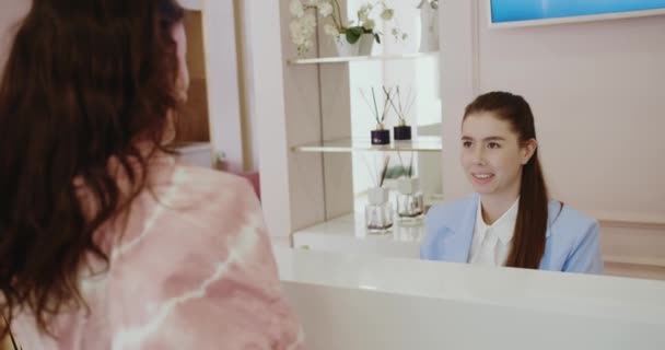 Jonge Receptioniste Kliniek Gesprek Met Vrouwelijke Cliënt Helpen Een Afspraak — Stockvideo