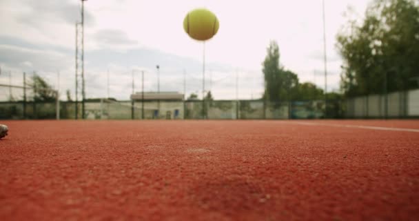 女性テニスプレーヤーは 裁判所から奉仕するラケットでボールを拾います 友人は屋外のカーペットコートでテニスをします レクリエーションのための週末と日曜日の活動 テニス — ストック動画