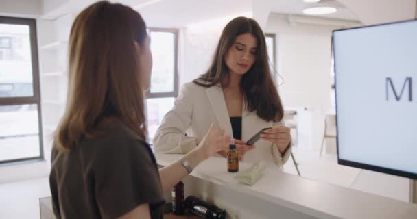 Kvinnelig Klient Velger Krem Ansiktsbehandling Skjønnhetssalongen Kvinnelig Konsulent Anbefaler Profesjonelle – stockvideo