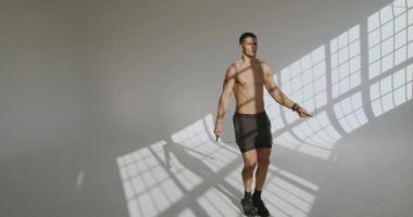 Atletik adam atlama halatıyla atlama egzersizi yapıyor. Kaslı vücutlu genç bir erkek kardiyo egzersizi yapıyor. Aktif ve sağlıklı yaşam tarzı kavramı.