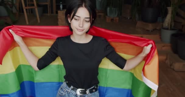プライドイベント Lgbtの権利 ライフスタイル Lgbtコンセプト Lgbtの女性は自宅のカメラに誇りを持って虹の旗を見せています 抱きしめて保持する ハッピーな女性と笑顔 セックスの多様性 — ストック動画