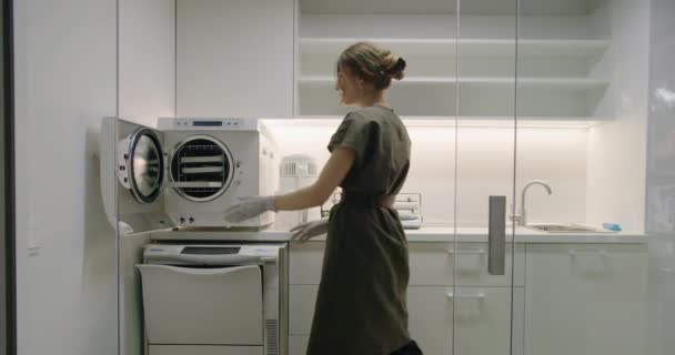 妇女为美容程序准备仪器 使用自动消毒器洗衣机和专用房间的高压灭菌和消毒工具 — 图库视频影像