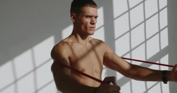 Konzentrierter Junger Mann Mit Athletischem Körper Der Studio Mit Widerstandsband — Stockvideo
