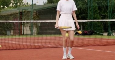 Genç bayan raket ve zıplayan topla tenis antrenmanı yapıyor. Tenis maçına hazırlanın. Aktif dişiler yaz günü dışarıda tenis oynarlar.