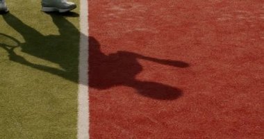 Tenis oynayan ve kil sahada raketle top oynayan bir kadının gölgesi. Kadınlar güneşli yaz günlerinde spor yapar ve topa vurmak için antrenman yaparlar. Aktif eğlence konsepti. Oyuncu yarışmaya hazırlanıyor