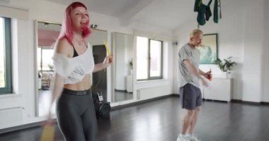 Genç adam ve kadın atlama halatıyla egzersiz yapıyorlar, stüdyoda dans ediyorlar. İp atlarken spor yapan çift. Aktif ve sağlıklı yaşam tarzı kavramı.