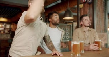 Delikanlılar barda bira içip maç izliyorlar. Neşeli erkek kaleyi kutluyor ve arkadaşlarına gülüyor, çünkü takımları futbol maçında kaybediyor.