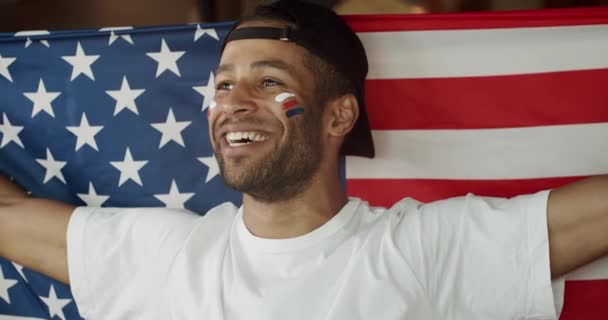 他的惊慌失措的男足球迷的画像 脸上涂着美国国旗 男子快乐观看足球比赛的服装及在酒吧为支持的球队欢呼 — 图库视频影像