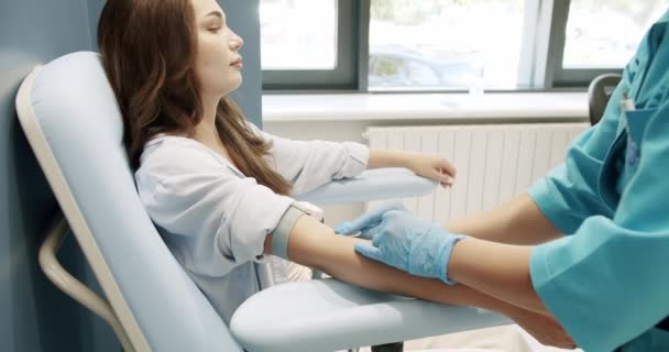 アームチェアに座っている若い女性患者 手袋の看護師は彼女の腕を消毒し 病院で血液検査の準備をする クリニックでの医療分析 — ストック動画