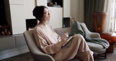 Düşünceli bir kadın rahat koltuğunda oturup not defterine not alıyor. Genç odaklı kadın kişisel günlüğüne düşünceler yazar. Kağıt defteri doldururken gelecekteki hedefleri ve planları düşünen kız