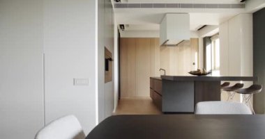 Sandalyeli yemek masası, tezgah ve bar tabureli mutfak adası modern iç ve panoramik pencereli şık bir dairede modern mobilyalar ve ev aletleri..