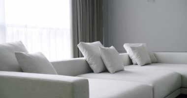 Yumuşak yastıklı rahat bir kanepe, mermer masa ve pencereli lüks oturma odasındaki perdeleri açık tonlu. Çağdaş dairede modern mobilyalar