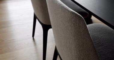 Lüks dairede döşeme ve ahşap yemek masası olan modern sandalyelere yakın çekim. Yemek odasında modern mobilyalar. Minimalist tarzda rahat koltuk