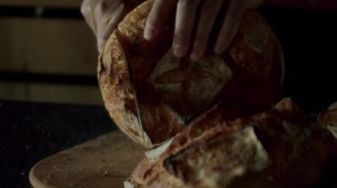 Fırıncının kıtır kıtır ekmeği bıçakla kıtır kıtır keserken çekilmiş görüntüsü. Erkek ellerine yakın çekim öğle yemeği için ev yapımı ekmek. Lezzetli geleneksel ekmek. 