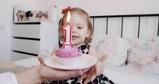 可爱的女婴穿着婚纱庆祝生日 在纸杯蛋糕上吹灭蜡烛 在孩子们的房间里坐在床上兴奋地拍手 快乐的幼儿和家人在家里庆祝一年 — 图库视频影像