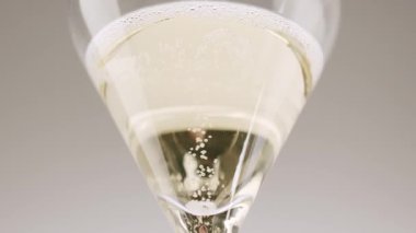 Anonymous person pouring champagne in glass. air bubbles in champagne glass. Low angle of unrecognizable person pouring fizzy champagne into elegant crystal glass against white background.