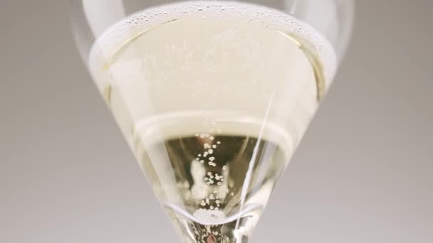 シャンパンをグラスに注ぐ匿名の人 シャンパングラスの気泡 白を背景としたエレガントな結晶ガラスにシャンパンを注ぐ認識できない人の低角度 — ストック動画