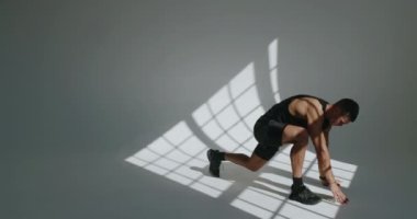 Spor yapan, spor yapan ve stüdyoda esneme hareketleri yapan genç bir adam. Spor kıyafetlerindeki kaslı erkek antrenmandan önce ısınıyor. Etkin yaşam tarzı kavramı