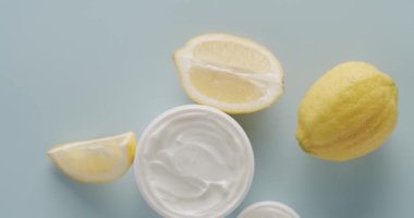 Kozmetik için limon meyveli beyaz şişe ve tüpler stüdyoda açık mavi arka planda. Doğal malzemelere dayalı kozmetik yağları. Cilt bakımı için doğal kozmetik ürünleri. Üst görünüm.