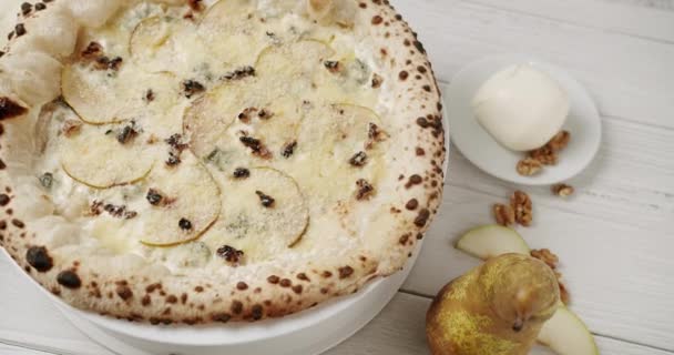大きなピザ4チーズと梨おいしいイタリアのナポリピザを食べる準備ができて白いテーブルと食材でフードサービス カメラズームアウト おいしいファーストフード パルメザンチーズとゴルゴンゾーラの梨 — ストック動画