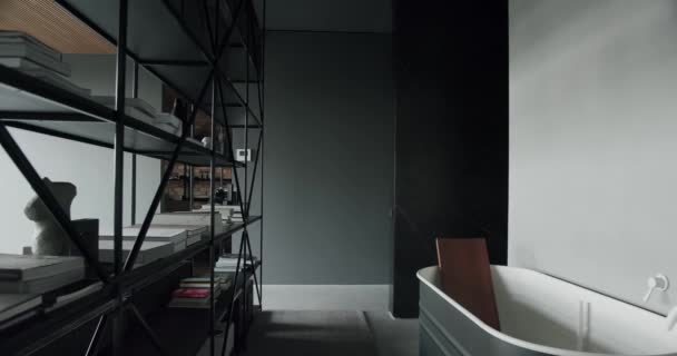 阁楼内部的风格别致的浴室 带有白色水龙头的现代浴缸和书架分隔了空间 宽敞的公寓 有书柜和浴室 室内设计理念 — 图库视频影像