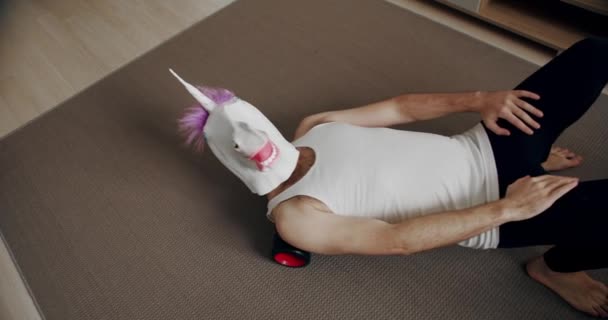 Vtipný Muž Maskou Jednorožce Cvičí Vzadu Válečkem Pro Myofáziální Relaxaci — Stock video
